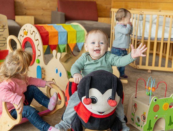 Drei Kleinkinder spielen mit buntem Spielzeug im gemütlichen Spielzimmer