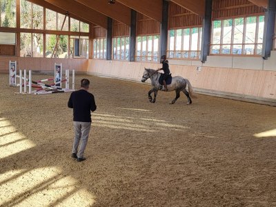 Reitlehrer zeigt einem Mädchen das Reiten in der Reithalle