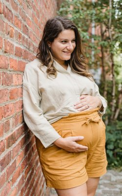 Eine schwangere Frau wie sie posiert und ihren Bauch hält