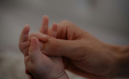 Hand einer Mutter wie sie die Hand eines Babys hält