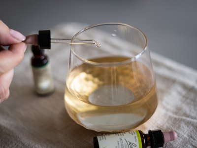 Glas mit Flüssigkeit wo etwas mit einer Pipette reingetropft wird