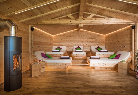 Kamin und Ruheraum aus Holz mit erhöhten Liegeflächen