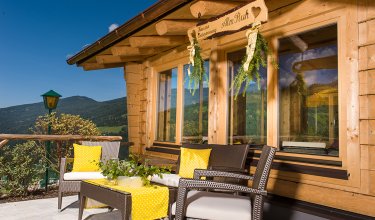 Terrasse mit Sitzgruppe, Bergblick und Schild „AlmRuh“