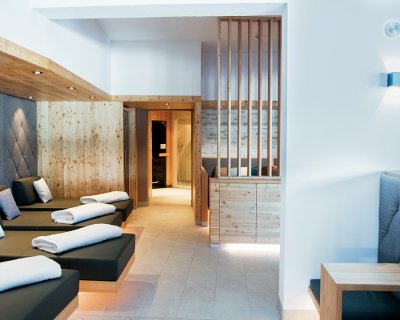 Helle Spa-Lounge mit Liegen, Holzverkleidung und gemütlichen Sitzplätzen