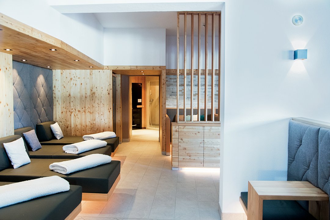 Helle Spa-Lounge mit Liegen, Holzverkleidung und gemütlichen Sitzplätzen