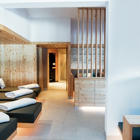 Helle Spa-Lounge mit Liegen, Holzverkleidung und gemütlichen Sitzplätzen