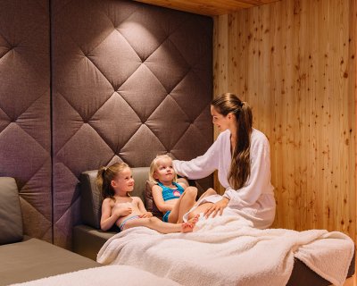 Mutter und Töchter entspannen auf Liegen im Spa-Bereich