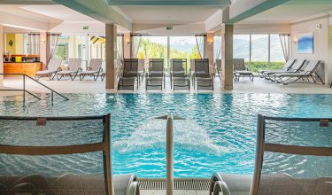 Blick auf das Hallenbad mit Wasserfall und Relaxliegen
