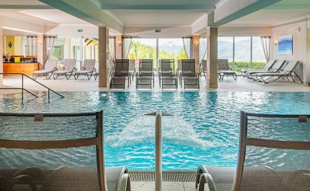 Blick auf das Hallenbad mit Wasserfall und Relaxliegen