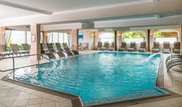 Hallenbad mit Massagedüse und vielen Liegestühlen