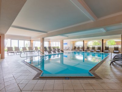 Großzügiger Indoor-Pool mit rundum angeordneten Liegestühlen
