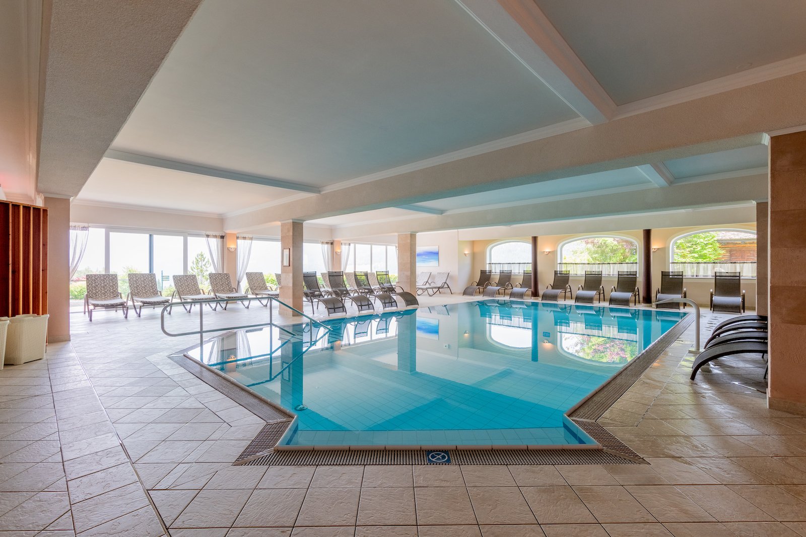 Großzügiger Indoor-Pool mit rundum angeordneten Liegestühlen