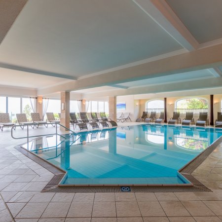 Großzügiger Indoor-Pool mit rundum angeordneten Liegestühlen