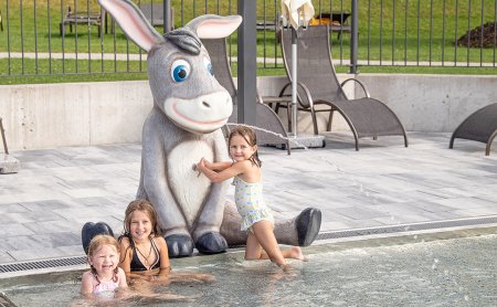 Drei Kinder spielen im Wasser bei Esel-Wasserspielfigur