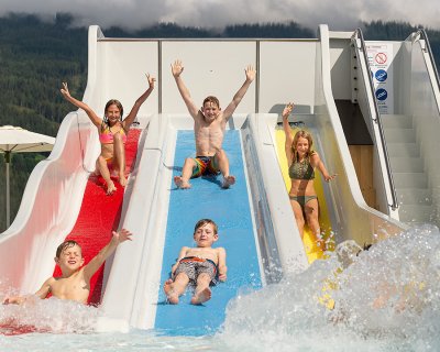 Sechs Kinder jubeln beim Rutschen ins Becken