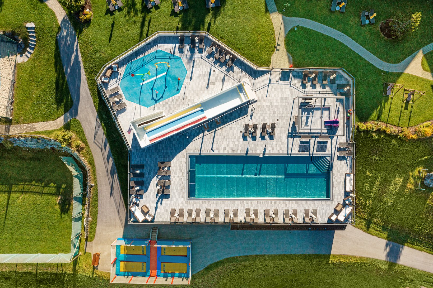 Draufsicht auf Pool, Rutschen und Wasserspielplatz mit Liegeflächen