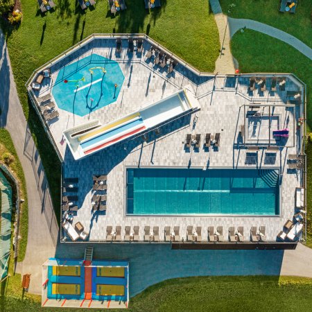 Draufsicht auf Pool, Rutschen und Wasserspielplatz mit Liegeflächen