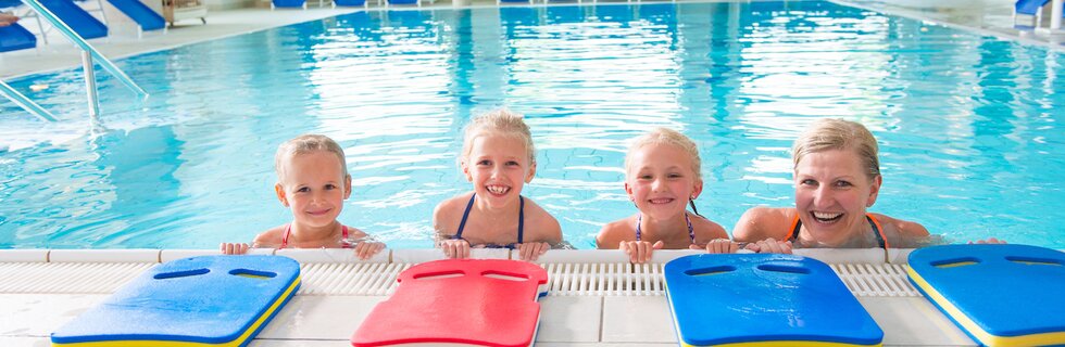 Kinder und Schwimmlehrerin lächeln in die Kamera