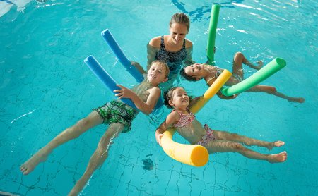 Kinder entspannen beim Schwimmkurs mit Poolnudeln