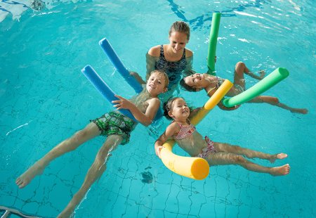 Kinder entspannen beim Schwimmkurs mit Poolnudeln