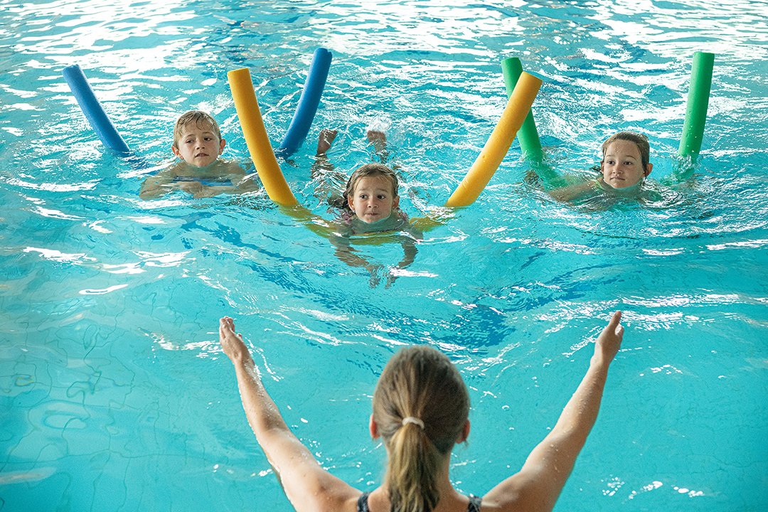 Kinder lernen schwimmen mit Anleitung im Hallenbad