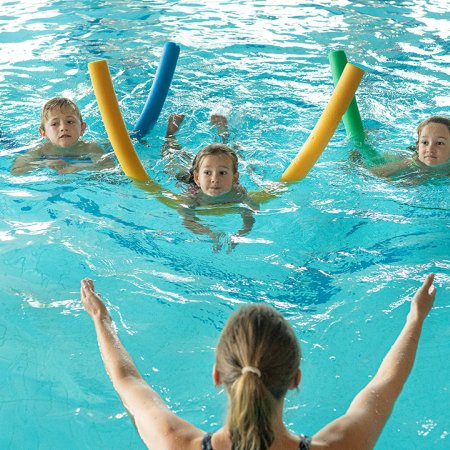 Kinder lernen schwimmen mit Anleitung im Hallenbad