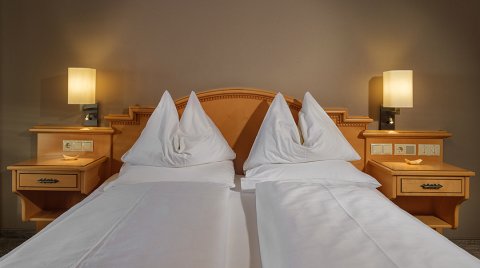 Doppelbett mit heller Holzverkleidung und zwei Nachttischen mit Lampen