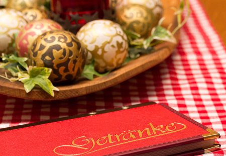 Weihnachtliche Tischdeko mit Kerze, Kugeln und roter Getränkekarte