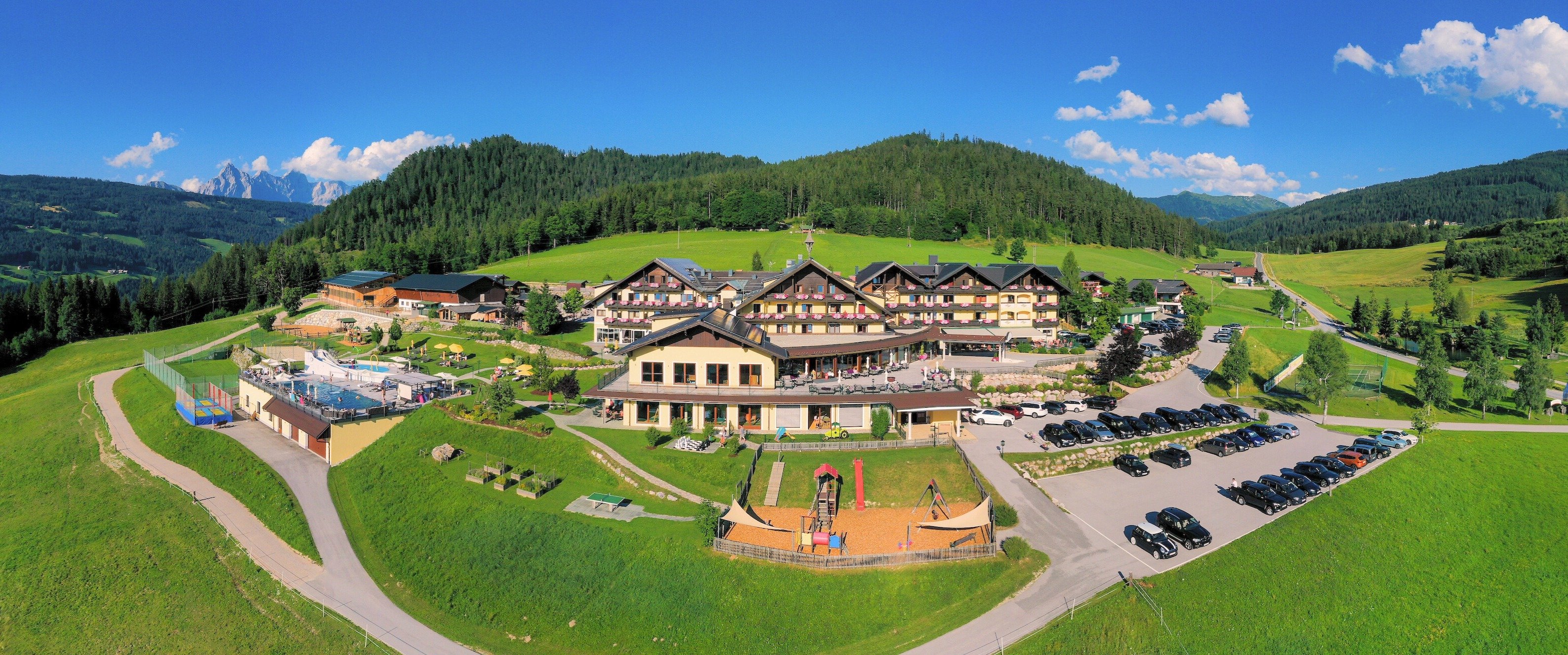 Hotelanlage mit Spielplatz, Pools und Liegewiese in alpiner Panoramalage