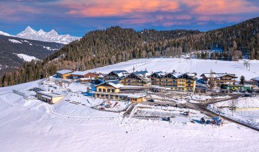Hotelanlage im Winter mit verschneiten Hängen und Spielplatz