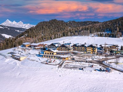 Hotelanlage im Winter mit verschneiten Hängen und Spielplatz