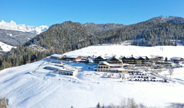 Hotelanlage mit Skipiste im Hintergrund und Blick auf das Dachsteinmassiv
