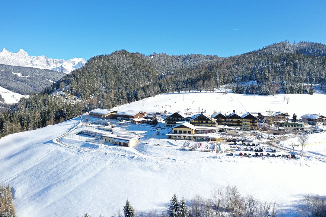 Hotelanlage mit Skipiste im Hintergrund und Blick auf das Dachsteinmassiv
