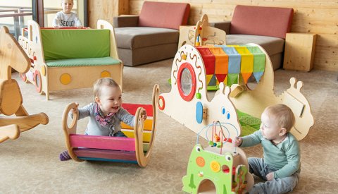 Drei Kleinkinder spielen fröhlich im bunt ausgestatteten Indoor-Spielbereich