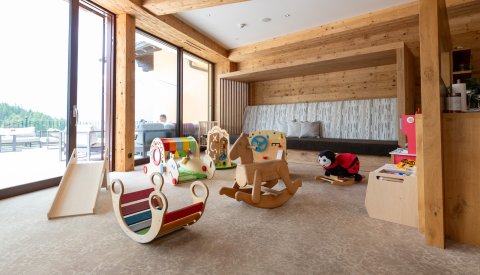 Heller Spielbereich mit Holzpferd, Rutsche und weiteren Spielgeräten