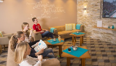 Jugendliche schauen im gemütlichen Raum gemeinsam Fernsehen
