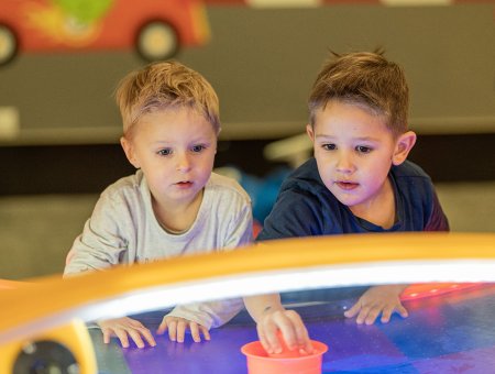 Zwei Jungen spielen konzentriert an einem Airhockey-Tisch