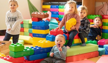 Mehrere Kleinkinder spielen zwischen bunten Bausteinen im Spielzimmer