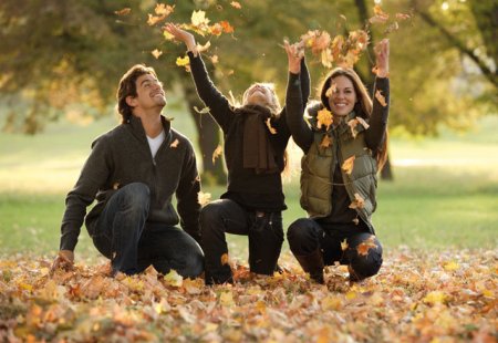 Familie spielt fröhlich im herbstlichen Laub im Park