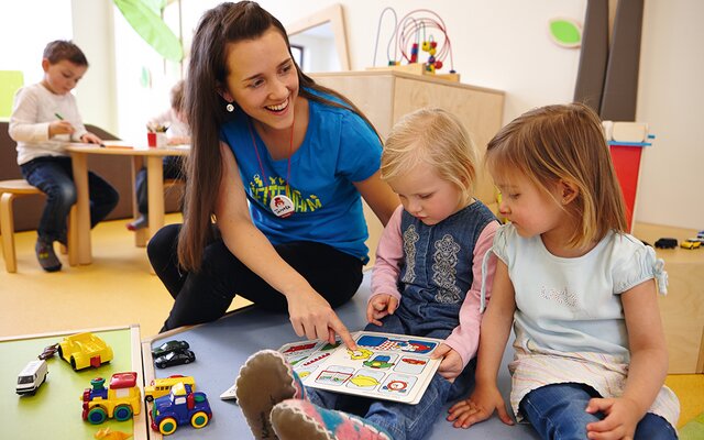 Kinderbetreuerin erklärt Kindern die Symbole in einem Kinderbuch