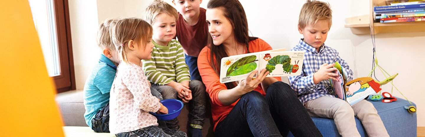 Kinderbetreuerin liest Gästekindern aus Buch vor