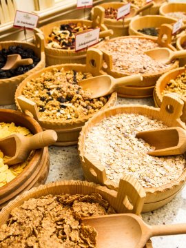 Verschiedene Müsli- und Getreidesorten in Holzschalen, jeweils mit Holzlöffeln.