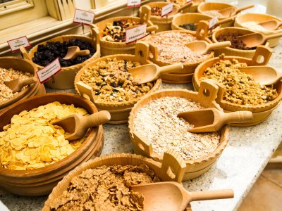 Verschiedene Müsli- und Getreidesorten in Holzschalen, jeweils mit Holzlöffeln.