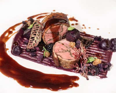 Rinderfilet im Blätterteigmantel, serviert mit Beeren und Sauce.