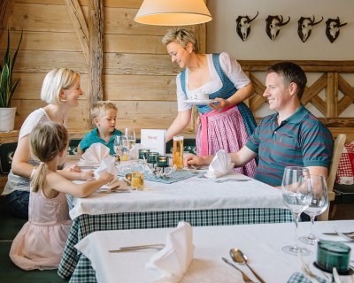 Eine Familie sitzt am Tisch, während eine Kellnerin ihnen eine Tasse serviert.