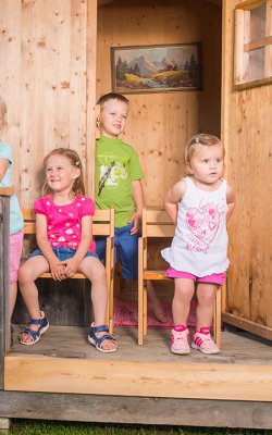 Vier Kinder stehen auf der Veranda eines Holzhauses und posieren für ein Foto.