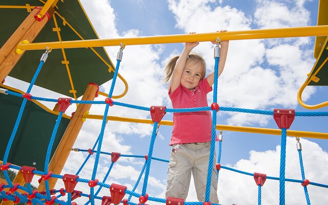 Kind beim Klettern auf dem Outdoor-Spielplatz