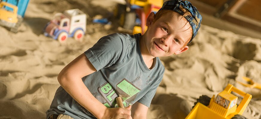 Kind beim Spielen im Sandspielhaus