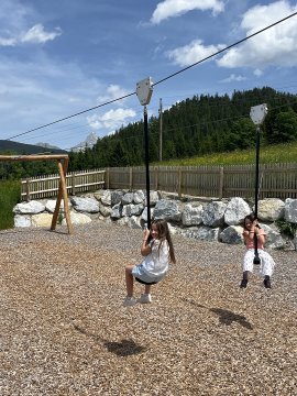 Zwei Mädchen fahren mit der Seilrutsche am Spielplatz.