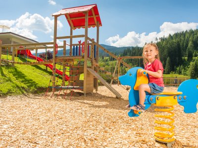 Ein Mädchen spielt auf einem Spielplatz auf einem springenden Spielgerät in Form eines Pferdes.